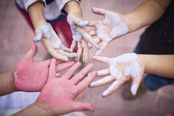 Hands of children covered in multicolor chalk