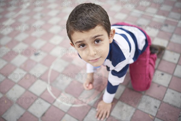 Hispanic boy drawing with chalk on sidewalk