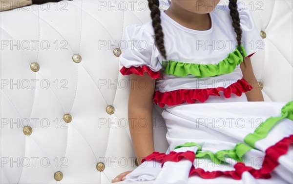 Girl with braids wearing festive dress on sofa