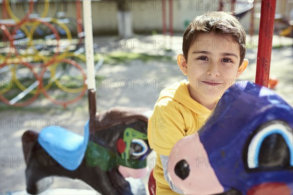 Hispanic boy on carousel at playground