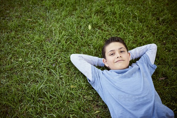 Smiling Hispanic boy laying in grass