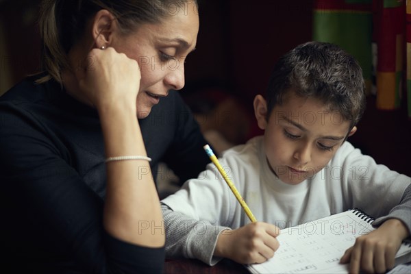 Hispanic mother watching son practicing writing alphabet