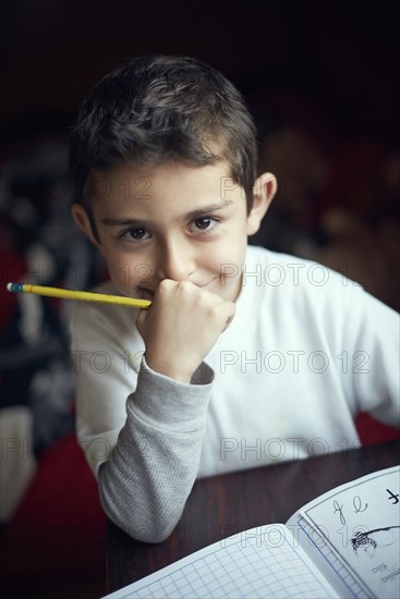 Smiling Hispanic boy practicing writing alphabet