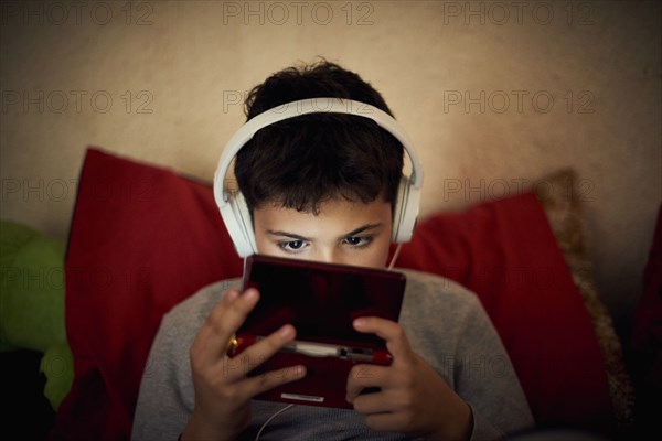 Hispanic boy listening to cell phone with headphones
