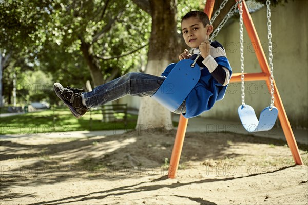 Hispanic boy on swing at park