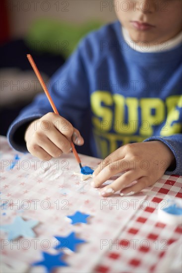 Hispanic boy painting stars at table