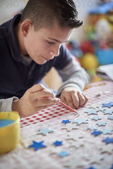 Hispanic boy painting stars at table