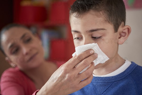 Hispanic mother wiping nose of son with tissue
