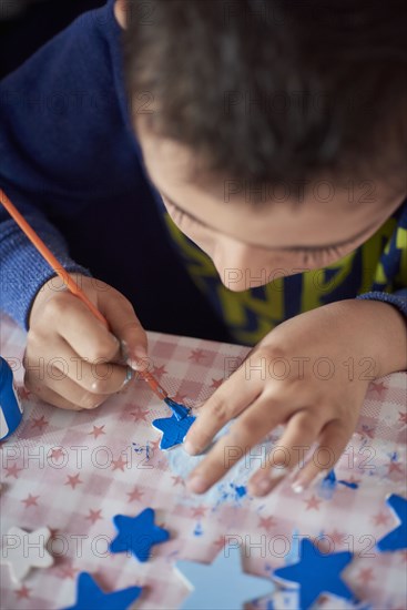 Hispanic boy painting stars at table