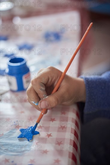 Hispanic boy painting stars at table
