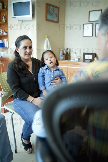 Hispanic mother and daughter with Down Syndrome talking to doctor