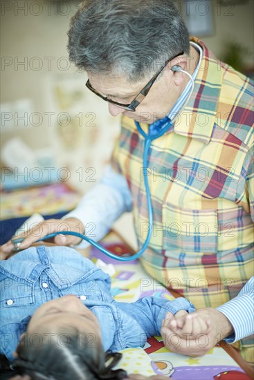 Hispanic doctor listening to chest of girl with stethoscope