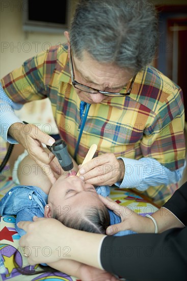 Hispanic doctor examining mouth of girl with Down Syndrome