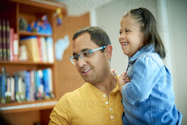 Hispanic father holding daughter with Down Syndrome