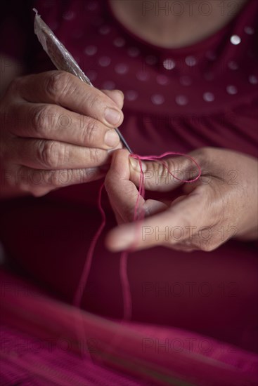 Hispanic woman weaving fabric on loom