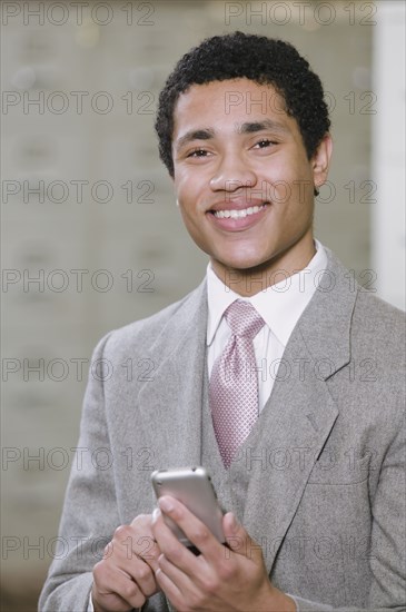 Mixed race businessman holding cell phone