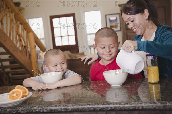 Hispanic mother and sons eating breakfast