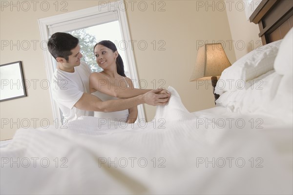 Hispanic couple making bed