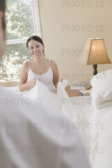 Hispanic couple making bed