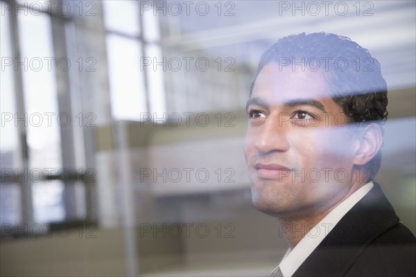 Mixed race businessman looking through window