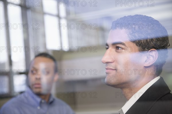Two businessman behind window glass