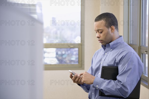 African businessman text messaging on cell phone