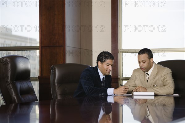 Two businessmen working in executive conference room