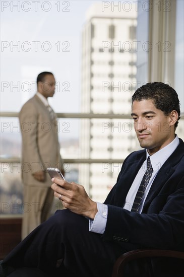 Mixed race businessman using cell phone