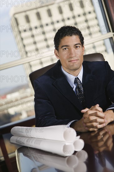 Mixed race businessman with blueprints