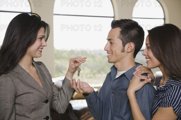 Realtor handing couple keys new home