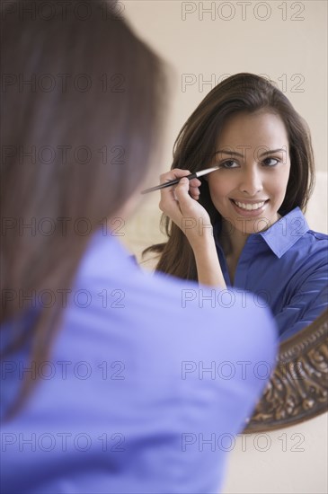 Hispanic woman applying eyeliner