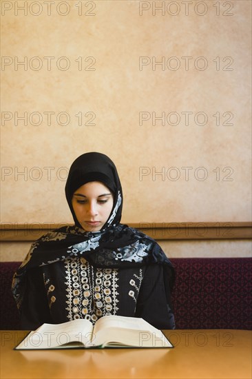 Middle Eastern teenager in headscarf reading book