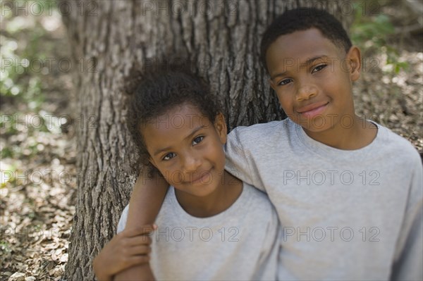 African boy and girl hugging against tree