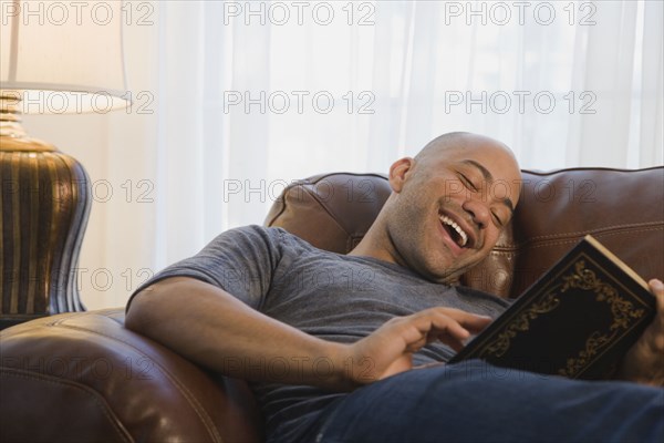 Mixed race man in armchair reading book