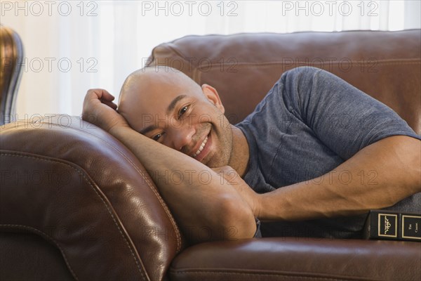 Mixed race man laying on sofa