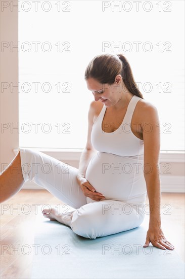 Pregnant woman sitting on yoga mat