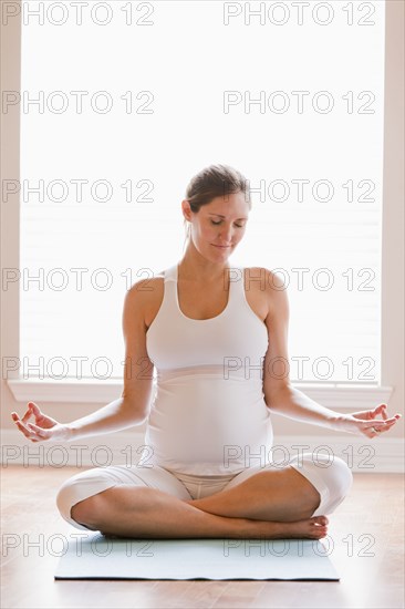 Pregnant woman meditating on yoga mat