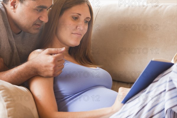 Couple reading together on sofa