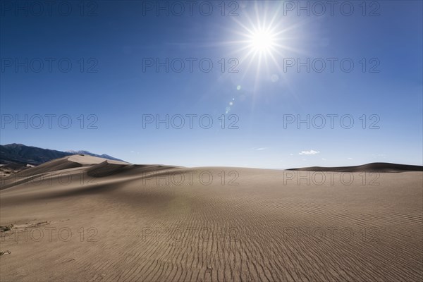 Sun in blue sky over sand dunes