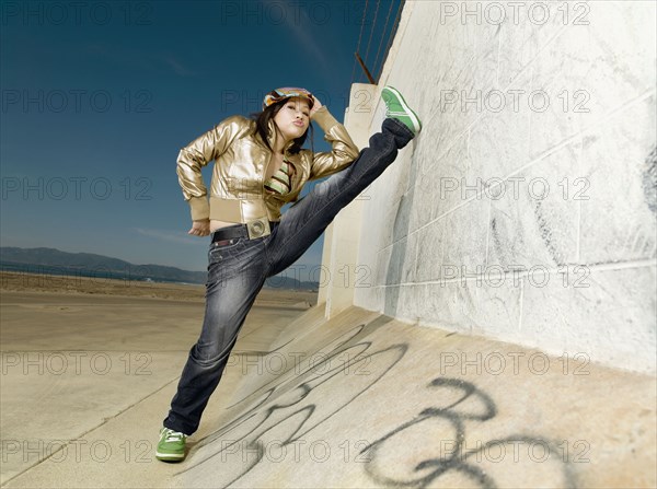 Asian woman stretching leg on wall