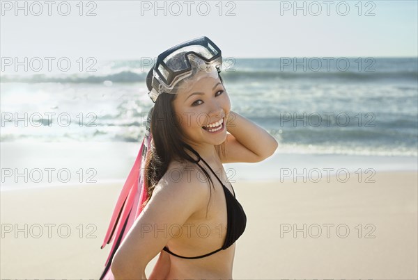 Asian woman wearing goggles at beach