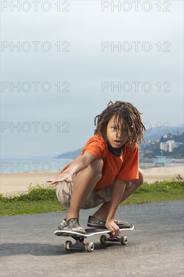 Mixed Race boy riding skateboard