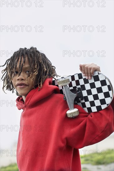 Mixed Race boy holding skateboard