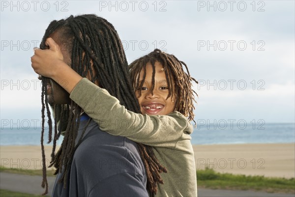 Mixed Race boy covering father's eyes