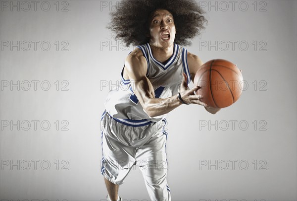 Mixed race basketball player holding basketball