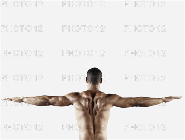 Bare chested mixed race man with arms outstretched