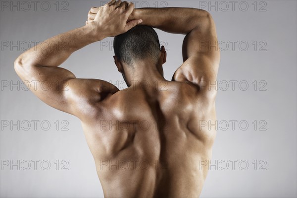 Bare chested mixed race man with arms raised