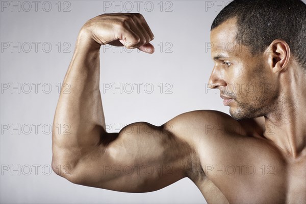 Bare chested mixed race man flexing biceps