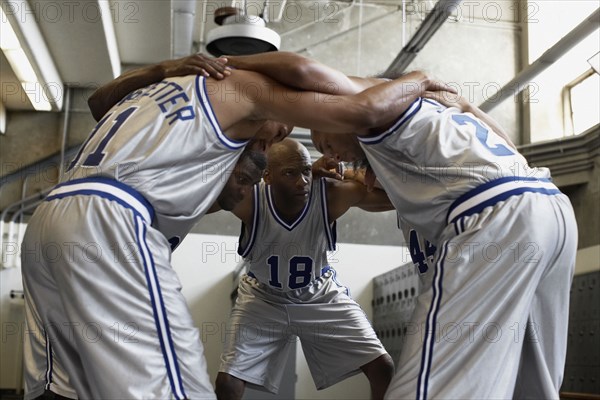 Multi-ethnic basketball players huddling in locker room