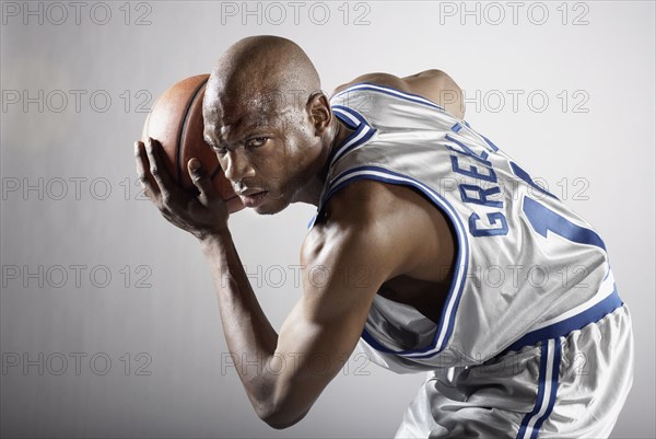 Sweating Hispanic basketball player holding basketball